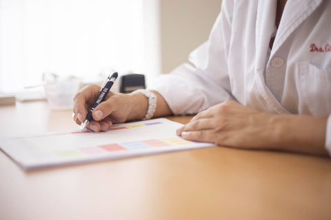 Doctora escribiendo una receta en su escritorio: pack médico con recetario y timbre