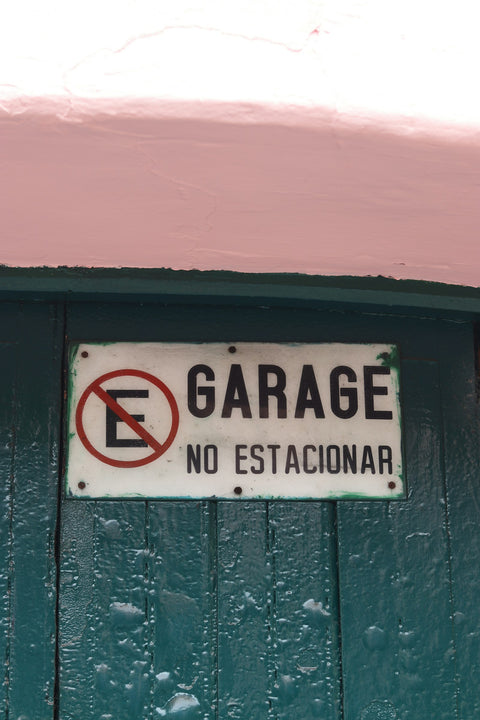 Señalética personalizada de no estacionar instalada en una puerta de madera verde